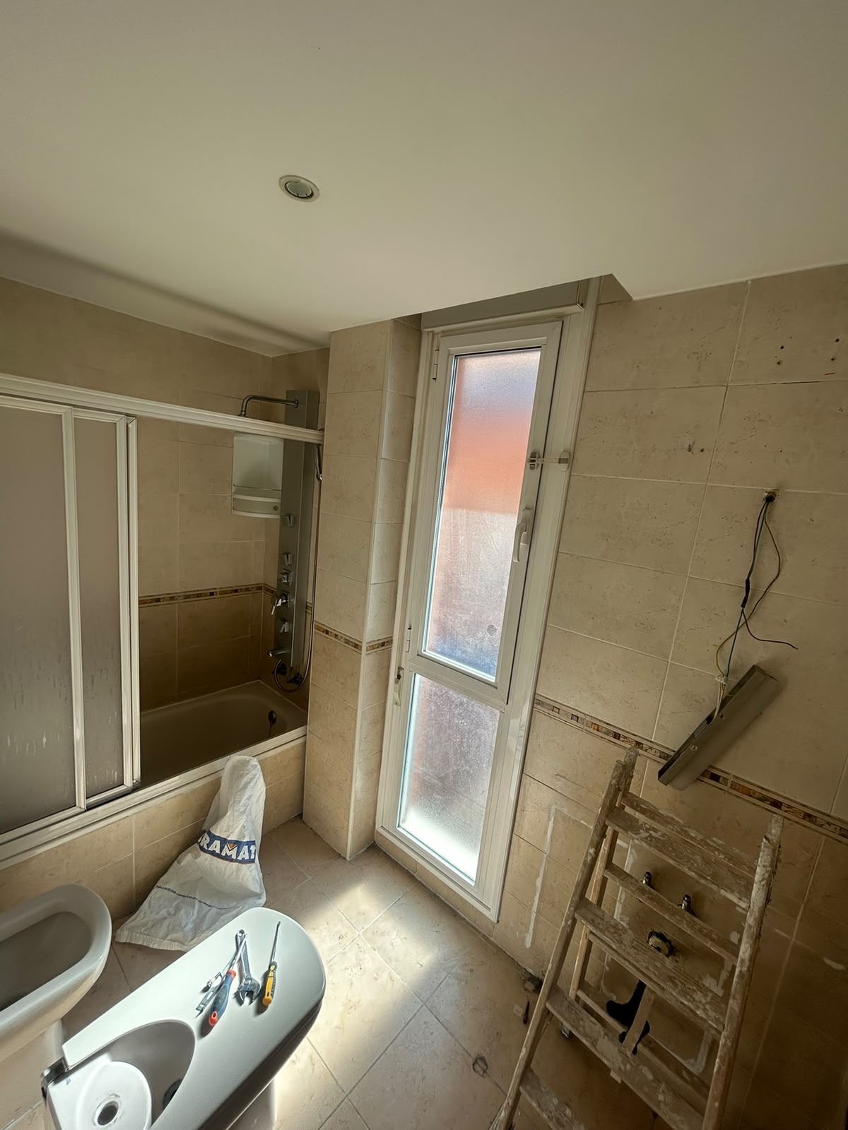 Baño con bañera y revestimiento original antes de la reforma